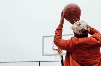 person holding basketball looking at basketball hoop system