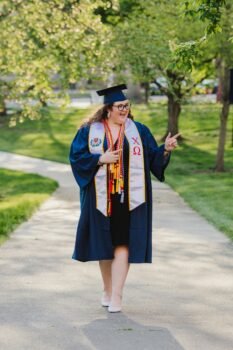 woman in blue academic dress standing on road during daytime