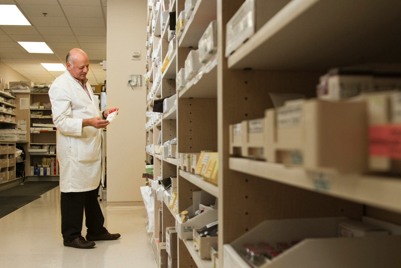 woman in white dress shirt and black pants standing near brown wooden shelf